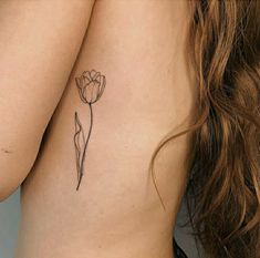 a woman's back with a tattoo on her left shoulder and a single flower in the middle