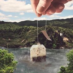 a hand holding a piece of paper over a body of water