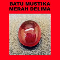 a red glass object sitting on top of a floor next to the words batu mustika merah delima