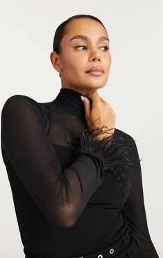 Introducing the elegant Feather Trim Shantel Top. With a fitted silhouette and sheer décolletage detail, this top will enhance your figure and add a touch of sophistication to your wardrobe. The luxurious black feathers on the cuffs will elevate any outfit, making you feel confident and chic. DETAILS Button closure on napeFabric: SuperstretchFitted silhouetteOstrich Feather TrimLong sleeve CONTENT AND CARE 87% Polyester 13% SpandexDry CleanImported MEASUREMENTS 23in/58.42cm from shoulderMeasurements from size S Skirt Coverup, Short Denim Skirt, Evening Tops, Feather Trim, Denim Outerwear, Outfit Making, Black Feathers, Tank Top Camisole, Knitting Accessories