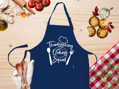 a blue apron with the words thanksgiving cooking and spoons on it next to some vegetables