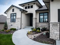 a house that is in the middle of some grass and flowers on the front lawn