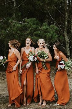 a group of women standing next to each other in front of some trees and bushes