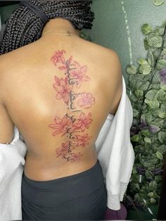 the back of a woman's body with flowers tattooed on her upper and lower back