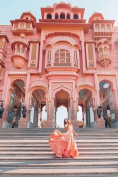 a woman in an orange dress is standing on some steps