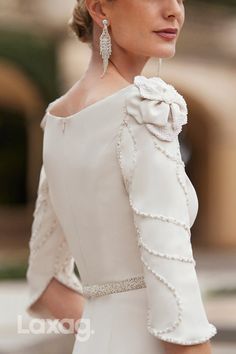 a woman wearing a white dress and earrings