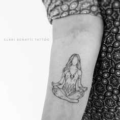 a woman with a tattoo on her arm sitting in a lotus position and looking to the side