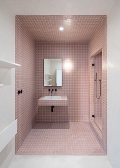 a pink tiled bathroom with a sink, mirror and bathtub in the corner on the wall