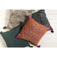 three decorative pillows with tassels and fringe on them, all in different colors