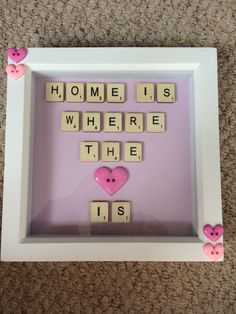 a scrabble frame with pink hearts and words that read home is where the heart is