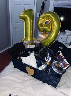 a large number balloon sitting on top of a bed next to a basket filled with items