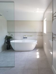 a large white bath tub sitting in a bathroom next to a walk - in shower