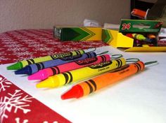 four crayons sitting on top of a table next to some boxes and markers