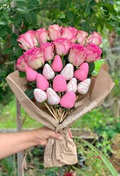 a bouquet of pink roses wrapped in brown paper is held by someone's hand