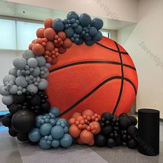 an inflatable basketball surrounded by black and gray balloons, stands on the floor