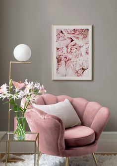 a living room with pink furniture and flowers in the vase on the side table next to it