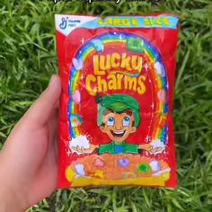 a hand holding a bag of lucky charms in the grass