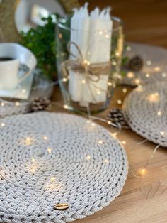 two crocheted placemats sitting on top of a wooden table next to candles