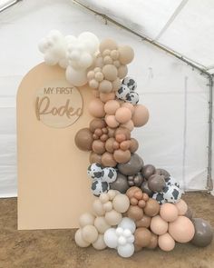 an arch made out of balloons with the words my first look written on it in front of a tent