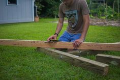 a man working on a wooden fence in the yard with his hands holding a piece of wood