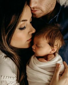 a man and woman holding a baby in their arms