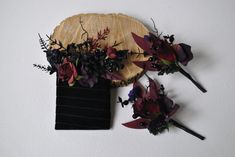 purple flowers and greenery are placed on a wooden plate next to a black comb