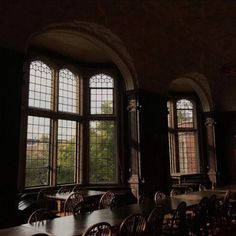 an empty room with many tables and chairs in front of two large windows that look out onto the trees outside