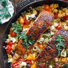 two salmons in a skillet with rice and vegetables