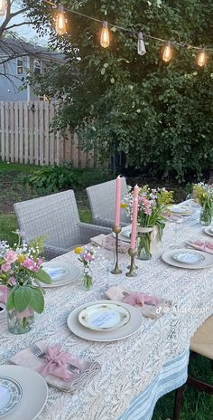 a table set with plates and candles for a dinner party in the back yard at dusk