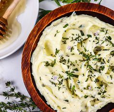 a wooden bowl filled with mashed potatoes and herbs