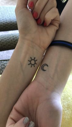 two people holding hands with tattoos on their arms and one has a sun and moon