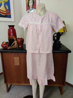 The perfect set of nightgown and short sleeved bed jacket in a cool poly cotton fibre by Lyn Maid in a vintage size 12. It was made in Hong Kong late 60s or early 70s. The nightie is above the knees with a hem ruffle and a two button closure at the front. It is sleeveless, edged in a white trim on the neck and armholes and beautifully machine embroidered in white. The jacket is short sleeved and has the same embroidery. It possibly is unworn and is in very good condition. Measurements are Nighti Feminine Pink Cotton Sets, Vintage Pink Spring Sets, Feminine Pink Daywear Set, Vintage Cotton Sets For Daywear, Vintage Short Sleeve Sleepwear For Loungewear, Vintage Pink Sleepwear For Pajama Party, Vintage Short Sleeve Nightgown For Pajama Party, Feminine Pink Short Sleeve Nightgown, Pink Nightie