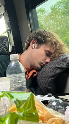 a man sleeping on a bus next to a bottle of water