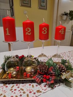 three red candles are sitting on a tray with christmas decorations and pine cones in front of them