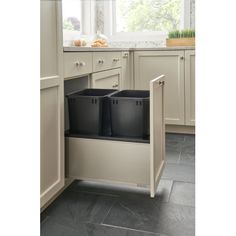 a kitchen with white cabinets and black trash cans in the bottom half of the cabinet