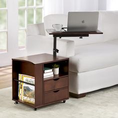 a laptop computer sitting on top of a wooden table next to a white couch in a living room