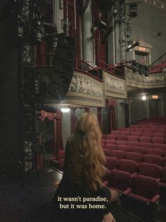 a woman standing in front of an auditorium with red seats and the words it doesn't paradise, but it was home