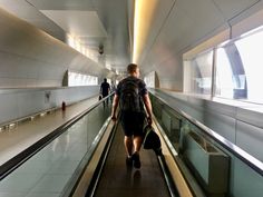 a man walking down an escalator carrying a backpack