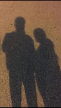 the shadow of two people standing next to each other