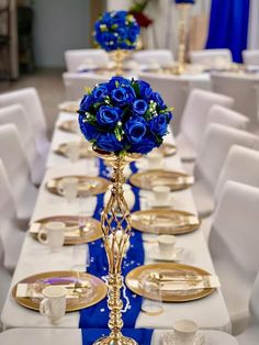 a long table set with blue roses and gold place settings for an elegant dinner party