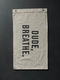 a piece of paper with the words breathe on it hanging from a black wall next to a pair of scissors