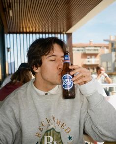 a young man drinking a beer from a bottle