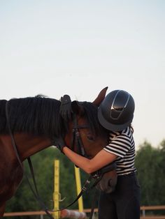 a woman in striped shirt petting a brown horse