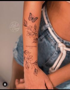 a woman's arm with flowers and butterflies tattooed on the arm, in front of her