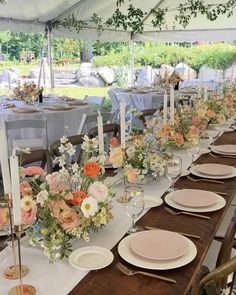 a long table is set up with plates and place settings for an outdoor wedding reception