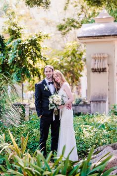 a bride and groom pose for a wedding photo in the garden at their outdoor venue