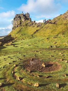 people standing on the top of a grassy hill with rocks and grass in the foreground