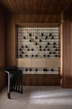 a room with wooden paneling and two black chairs in front of the wall that has several rows of buttons on it