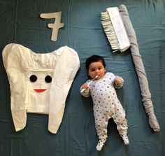 a baby laying on top of a bed next to a toothbrush and other items