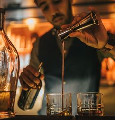 a man pouring some drinks into glasses